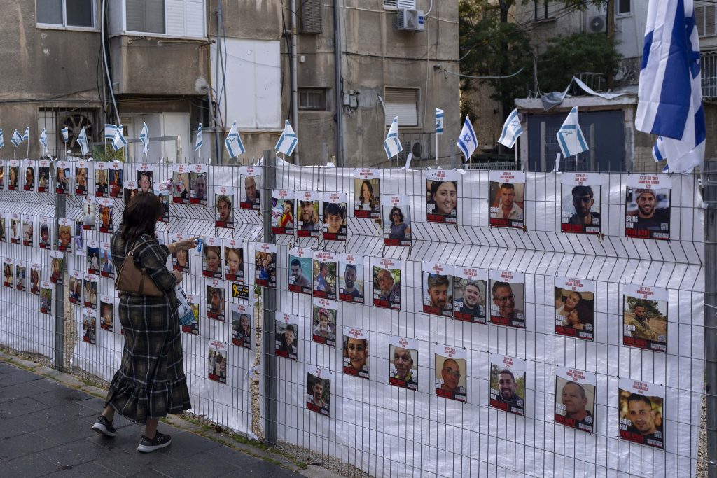 En kvinna tittar på bilder på personer som tagits som gisslan av Hamas (FOTO:AP via TT)